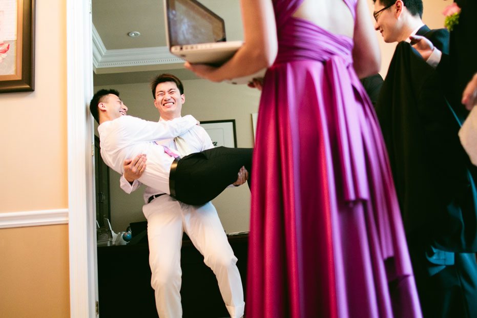 wedding photojournalist captures the groom as he carries his best man at a Toronto wedding